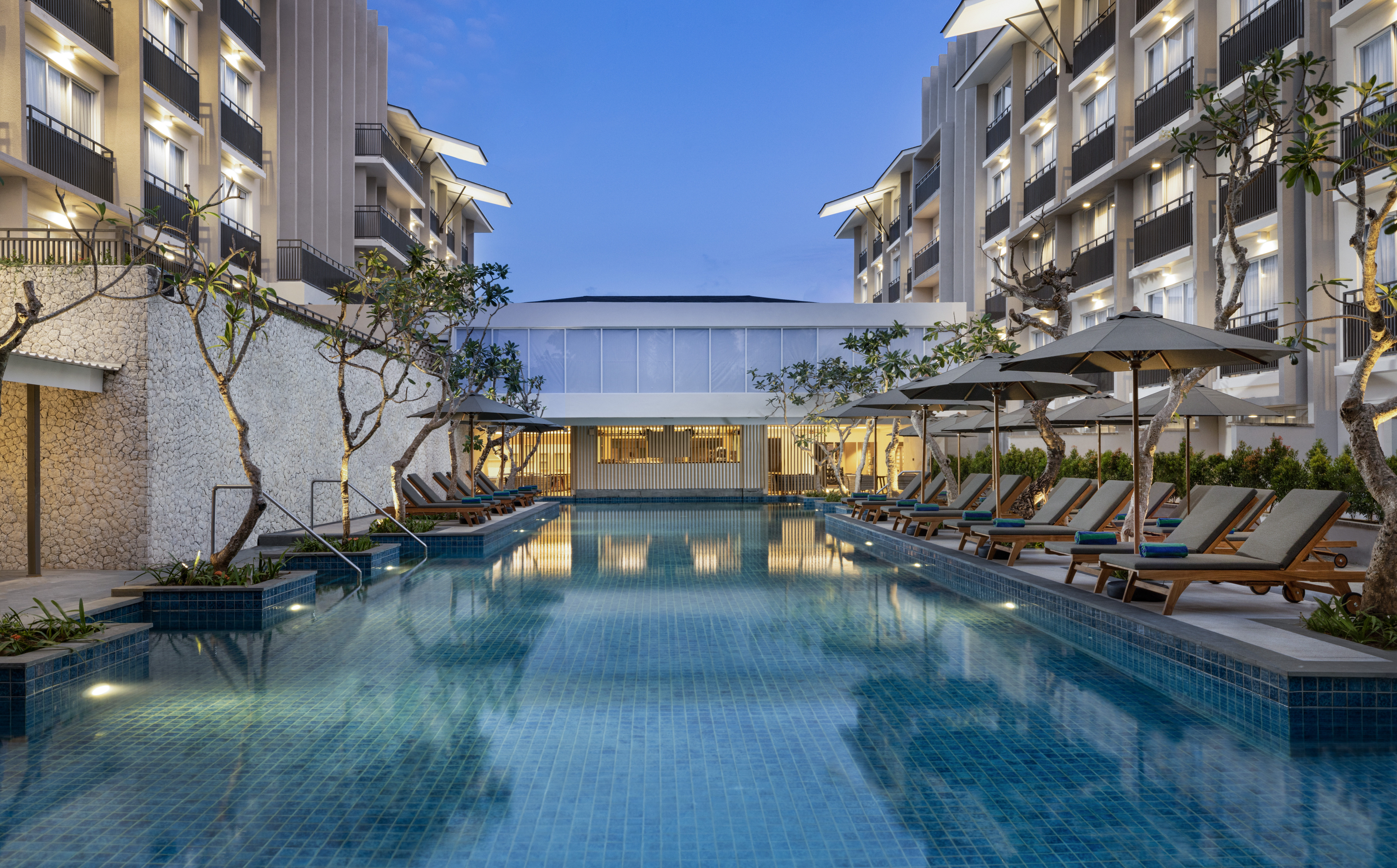 An evening view of the pool with lounge chairs and umbrellas