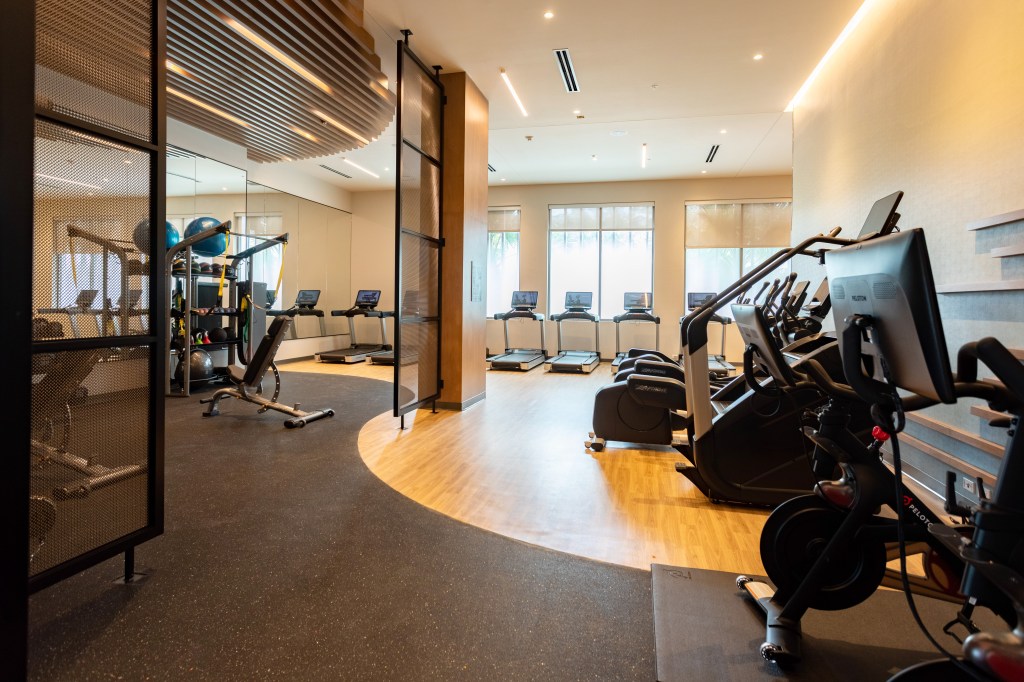 A gym with various equipment including treadmills, stationary bike, stair stepper, and free weights.