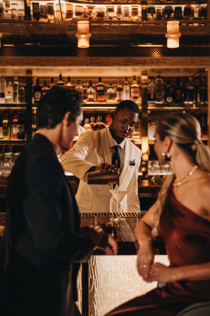 A couple being served at the bar by a bartender