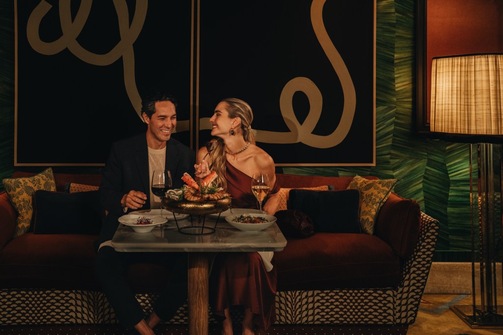 A couple eating dinner at a table, smiling at each other