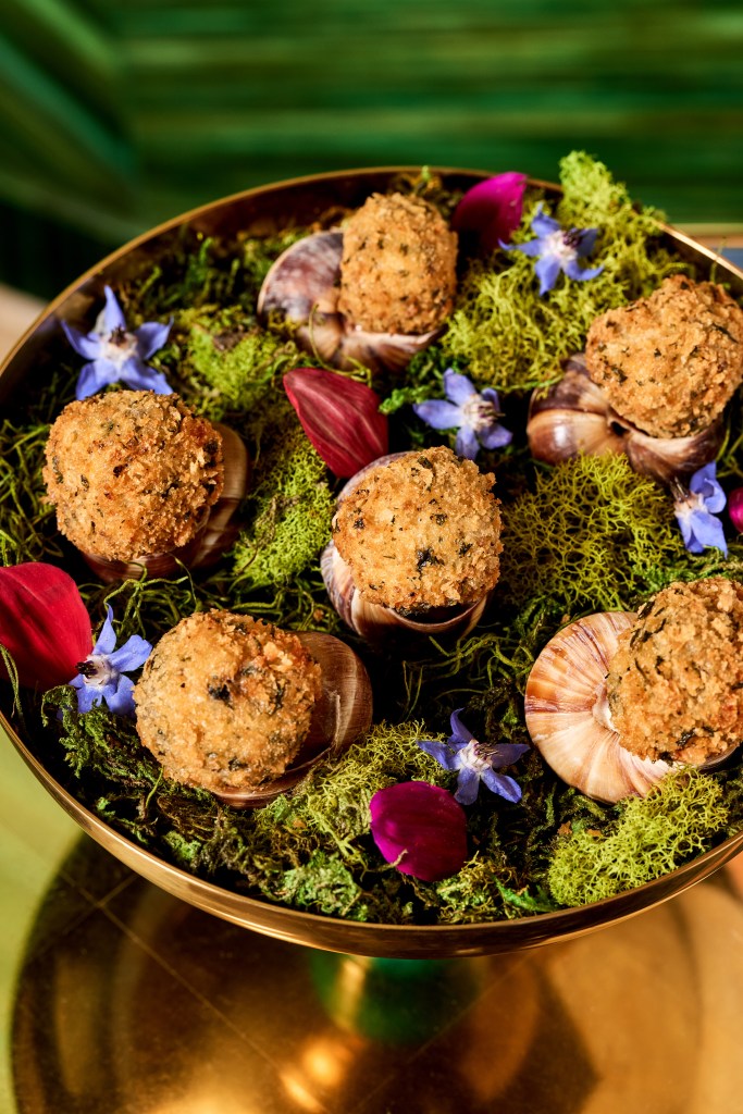 Escargot Poppers plated in a bed of greenery and edible flowers
