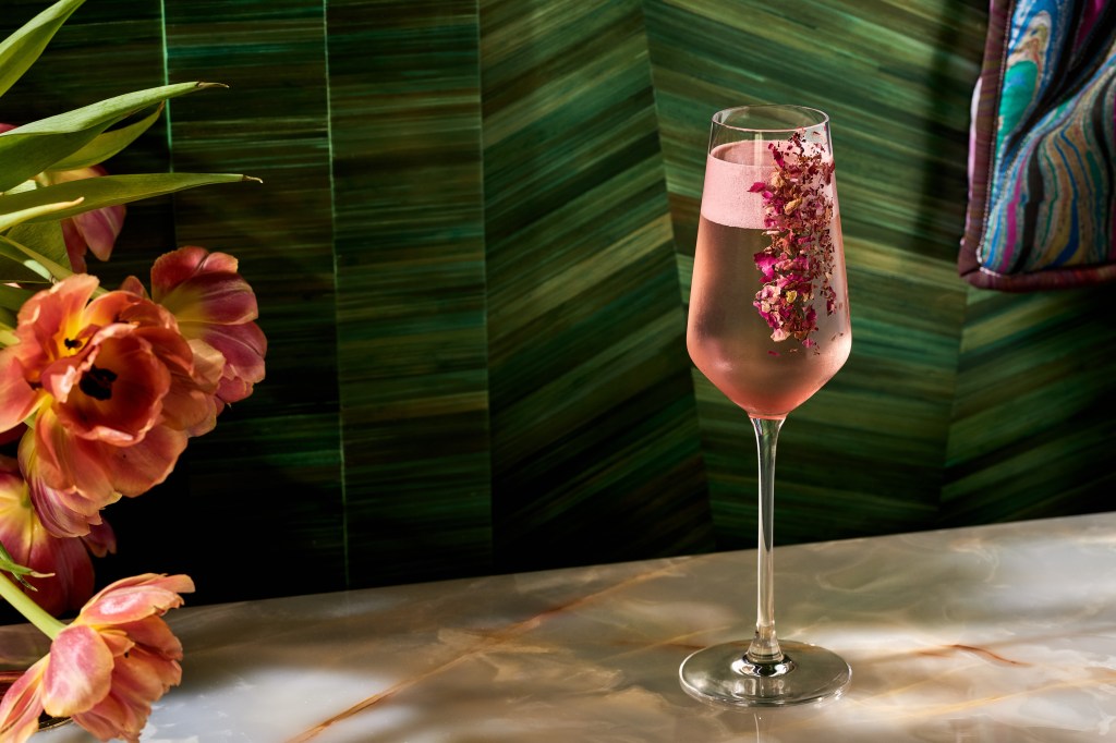 A pink specialty cocktail with floral decoration