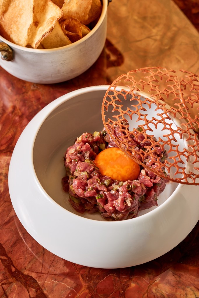 Steak Tartare in a small bowl with chips on the side