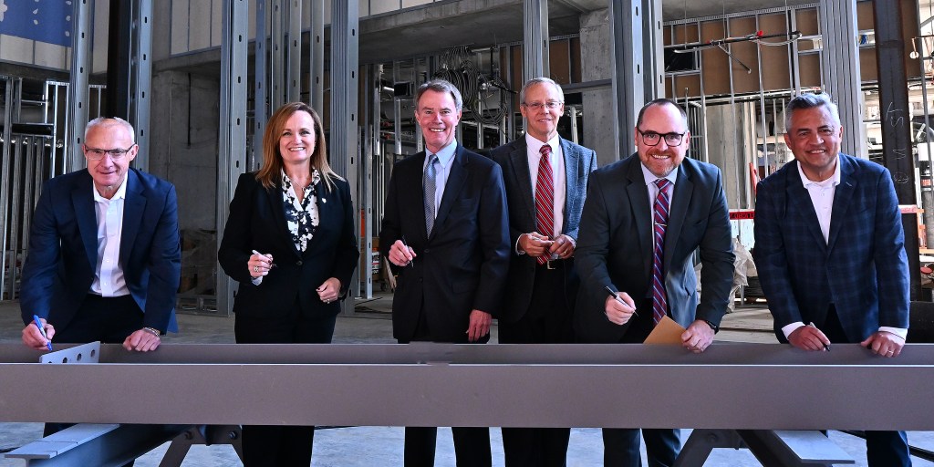 Signia by Hilton Indianapolis topping off ceremony and beam signing - From L-R: Gary Steffen, senior vice president and global category head, Hilton’s Full Service Brands; Kathy Heneghan, general manager, Signia by Hilton Indianapolis; Mayor Joe Hogsett, City of Indianapolis; Bill Sewall, vice president, AECOM; Andy Mallon, executive director, Capital Improvement Board and Leonard Hoops, president &amp; CEO, Visit Indy.
