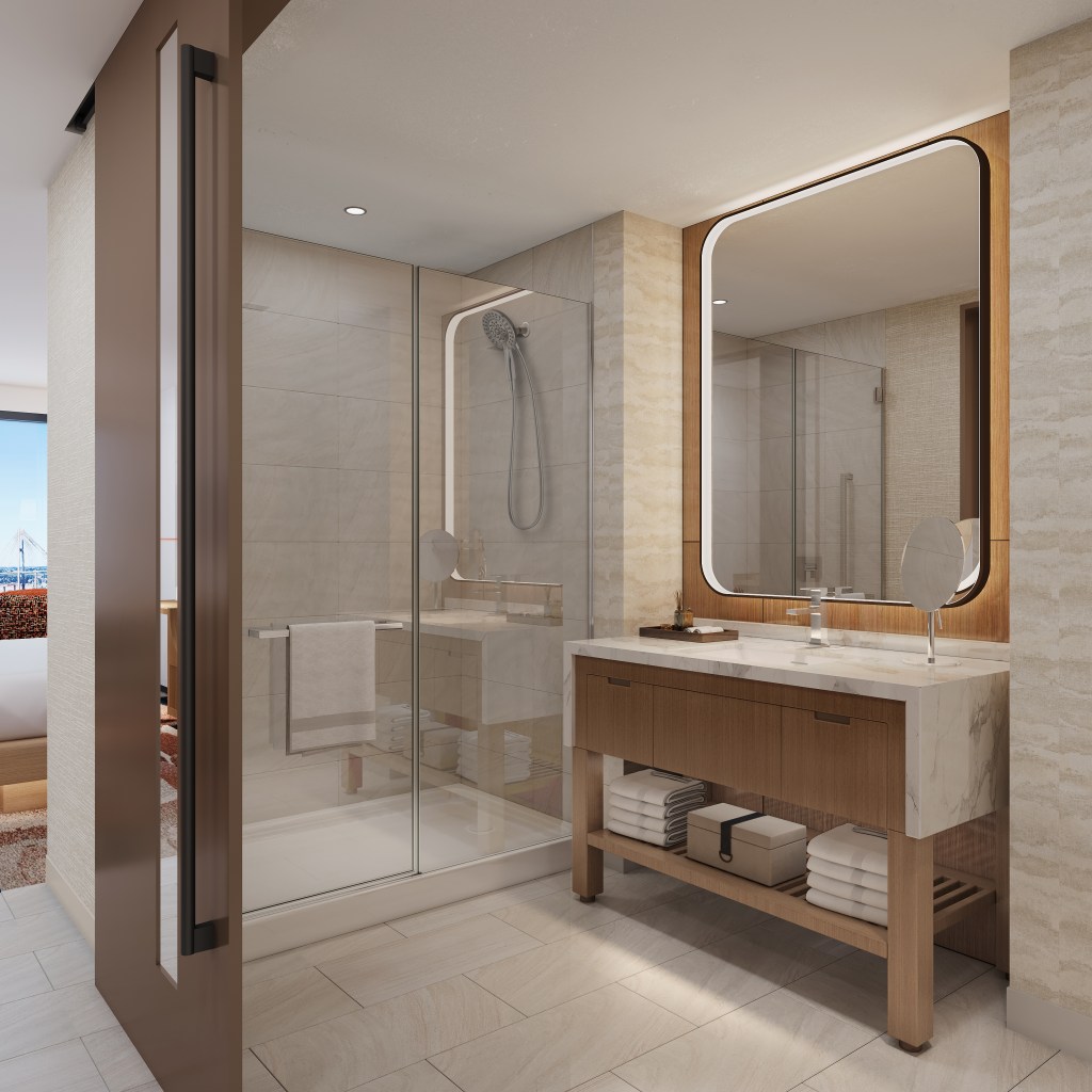 A bright bathroom with walk in shower, and large mirror over the sink