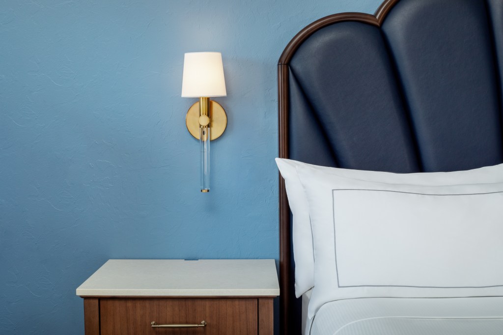 A close up of the bedside table and sconce above