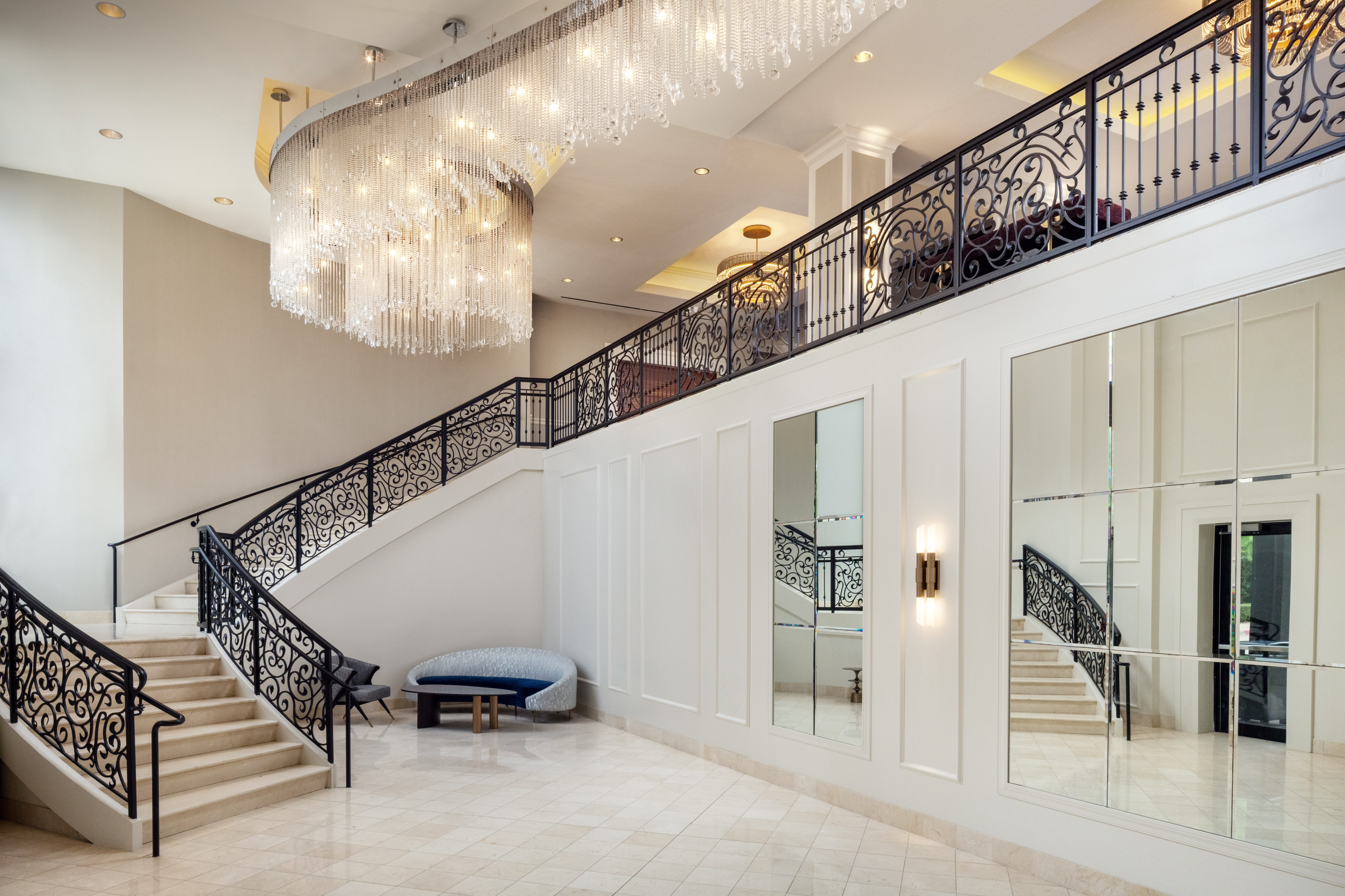 A staircase with intricate iron railing and artistic chandelier