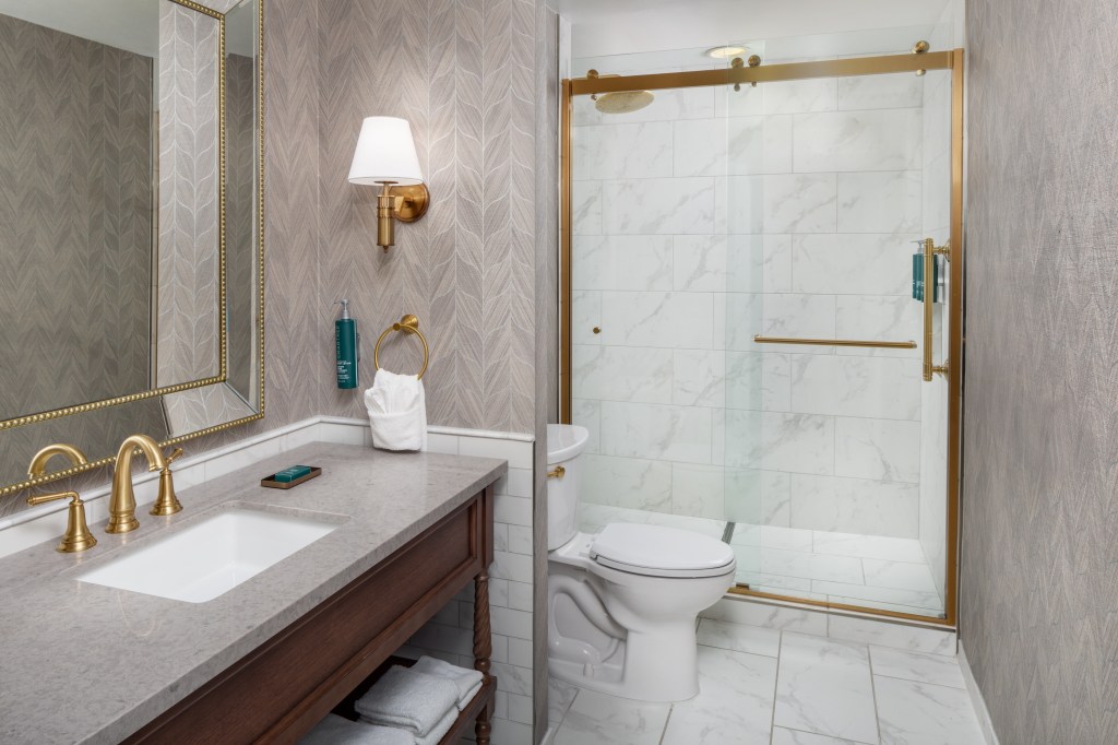A bathroom with large shower, toilet, and sink.