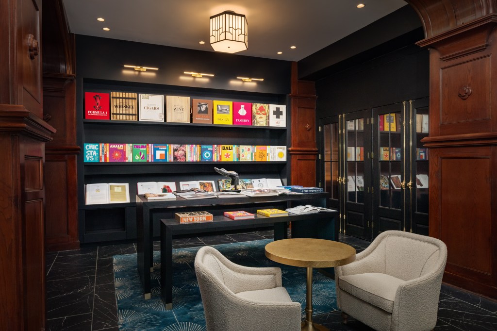A library with displayed books on shelves and table, and a couple of chairs