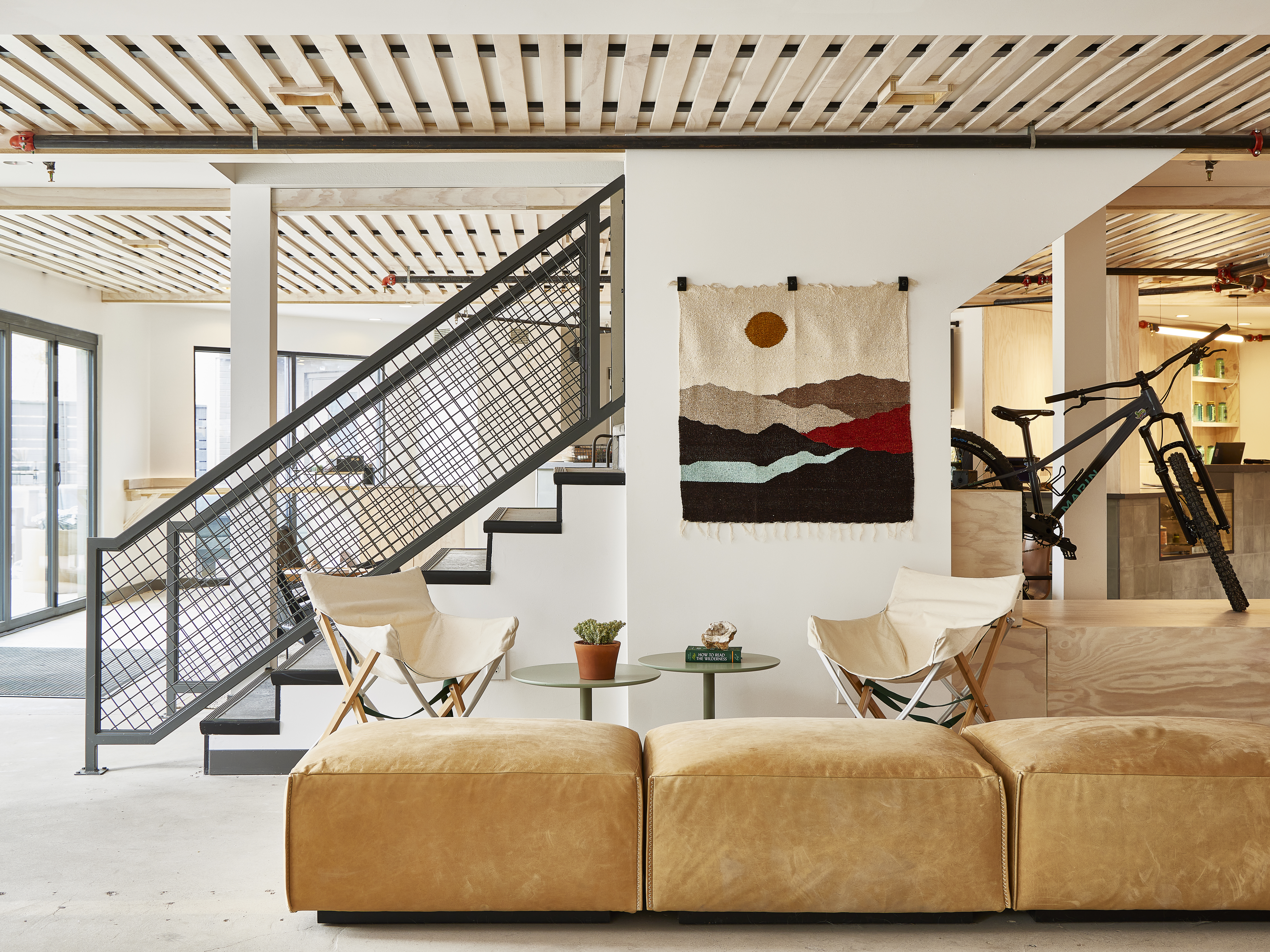 Slackline Moab, Outset Collection by Hilton - Lobby with leather seats, white walls, artwork with mountain scape, bicycle