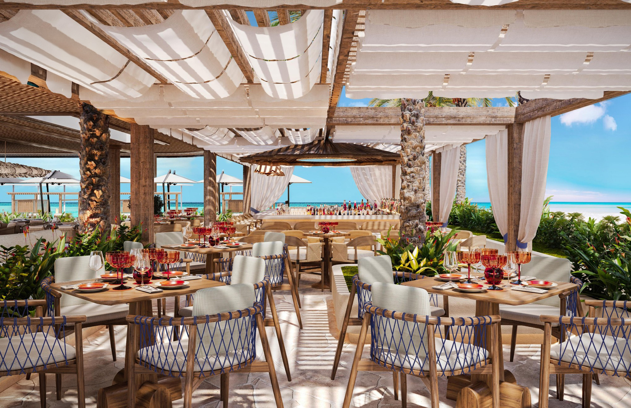 Tables and chairs set for dinner, covered by white canopies with the bar and beach in the background