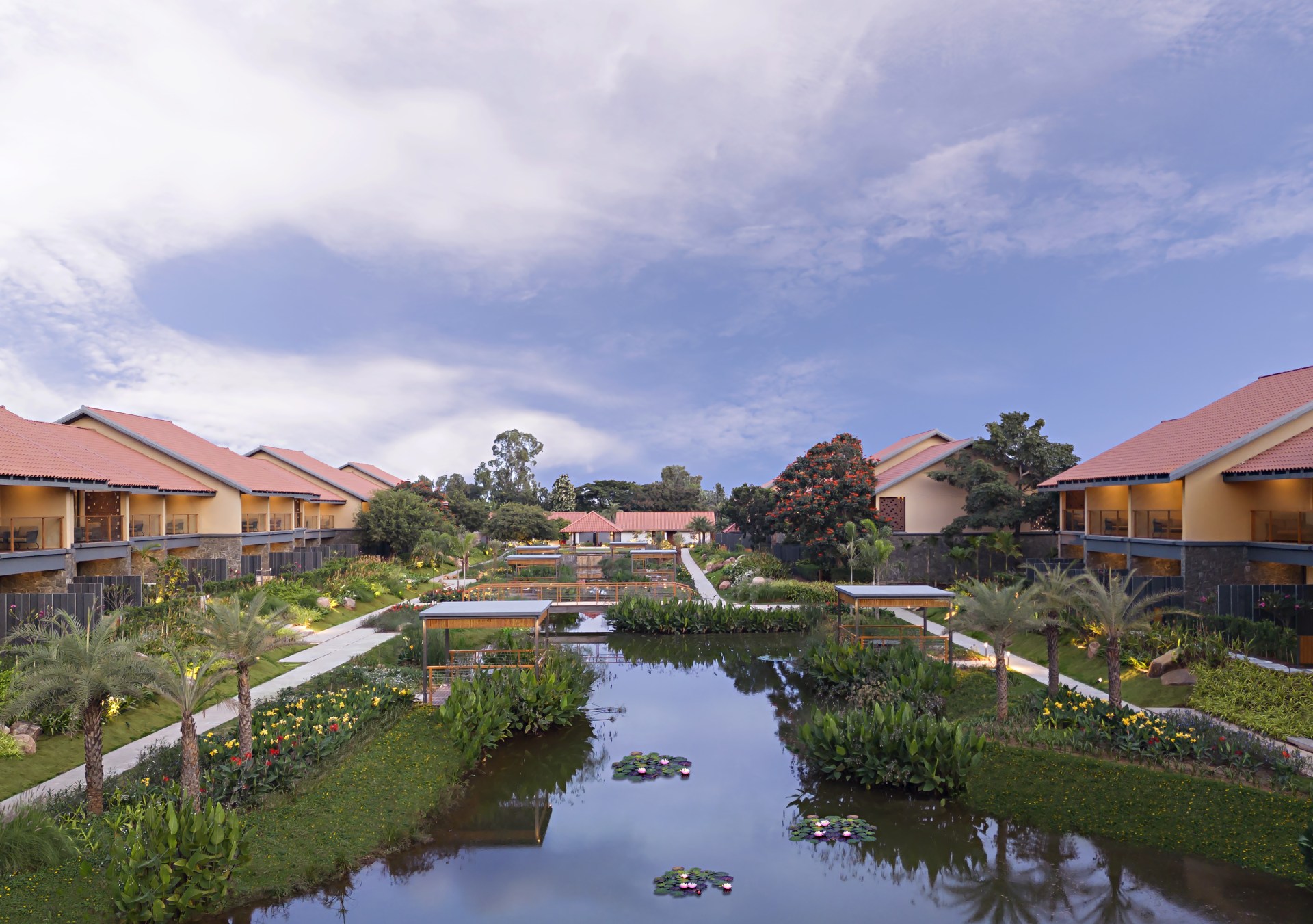 A creek surrounded by greenery runs between buildings of the hotel