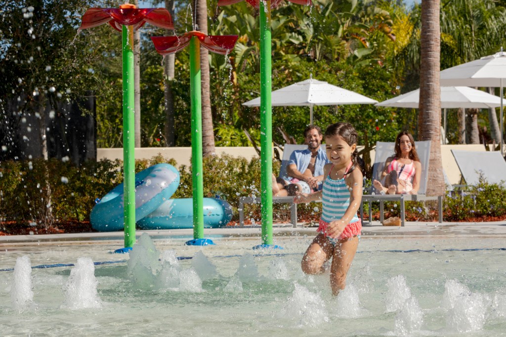 Hilton Orlando - Splash Zone - little girl playing in water splash zone while parents watch
