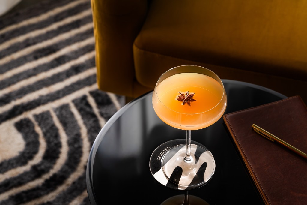 Tempo by Hilton - Pear Necessities - orange drink with star anise garnish in a glass on a table