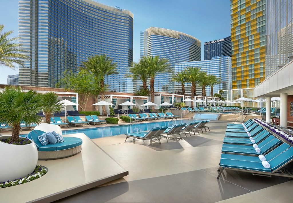 Waldorf Astoria Las Vegas - Pool, pool surrounded by lounge chairs, palm trees, Las Vegas skyline in the distance