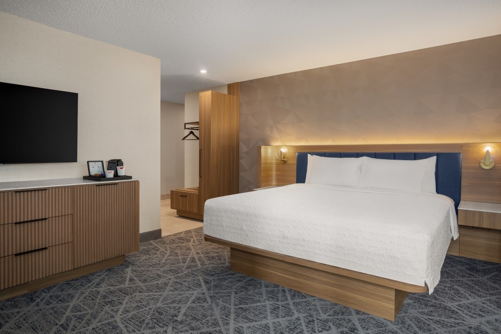 A guest room with bed, tv, wardrobe