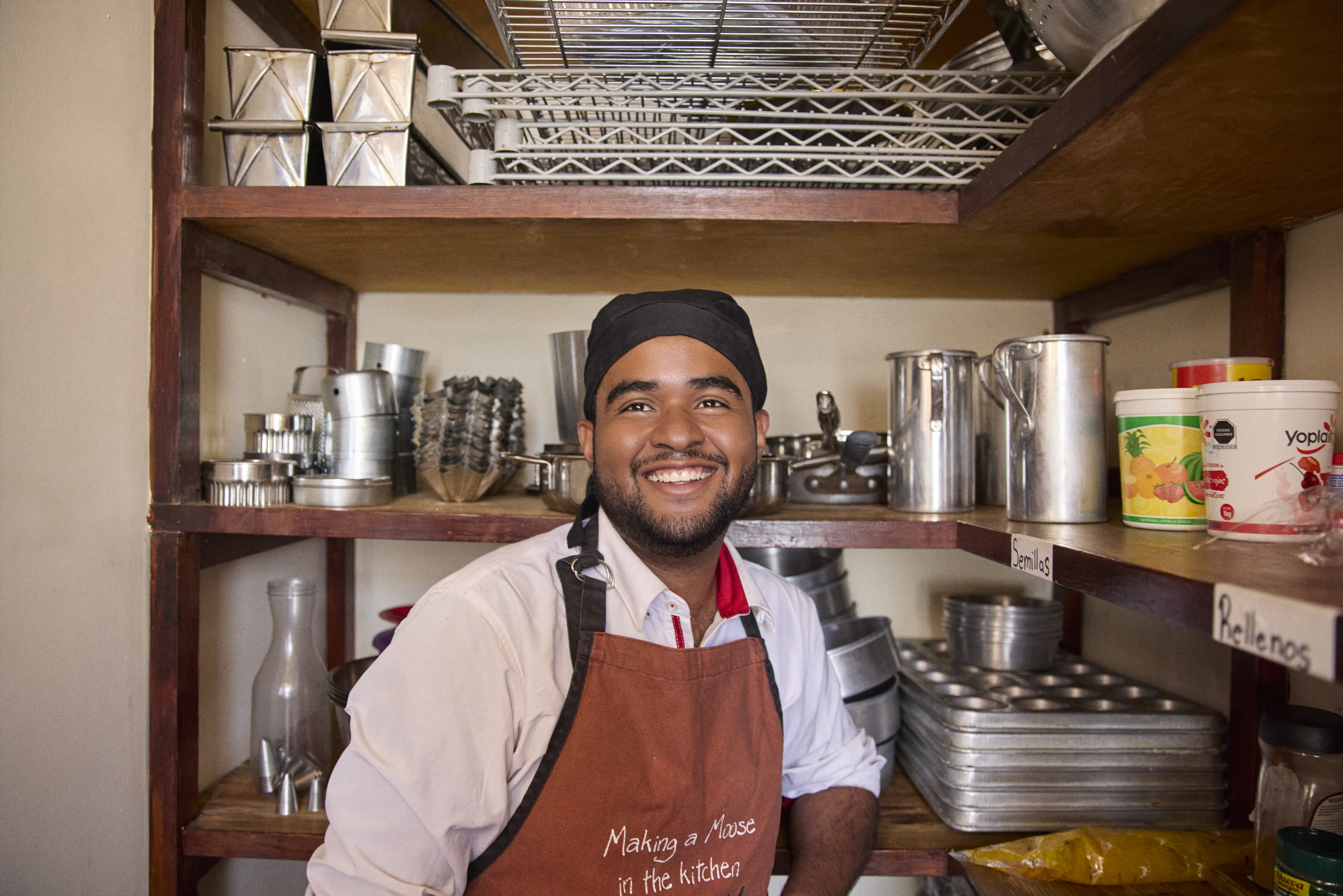 Person standing in kitchen smiling while wearing an apron with the words "Making a Moose in the kitchen" on the apron