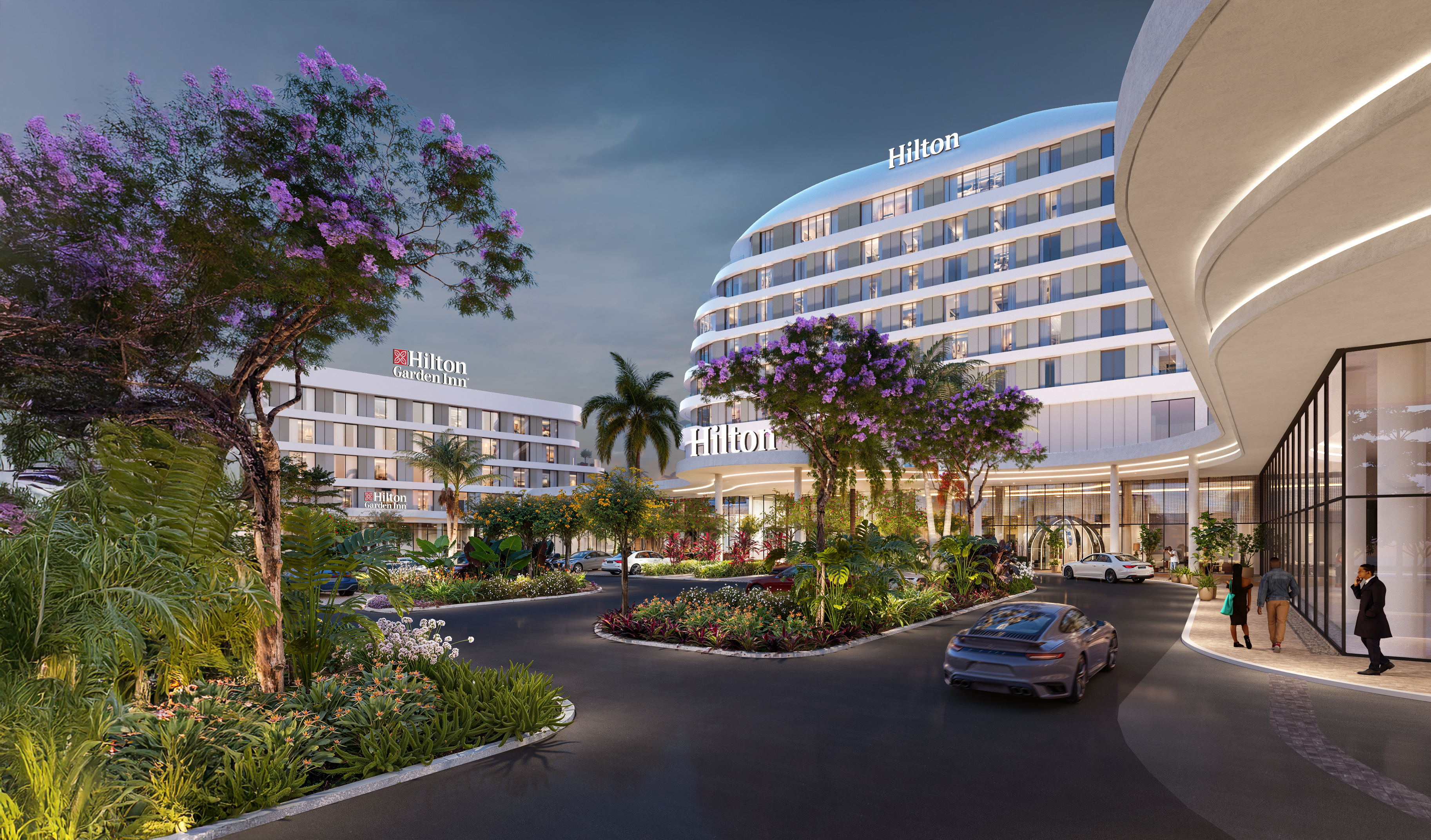 Modern Hilton hotel at dusk with curved glass design, landscaped entrance, luxury car, and illuminated signage in a vibrant urban setting.