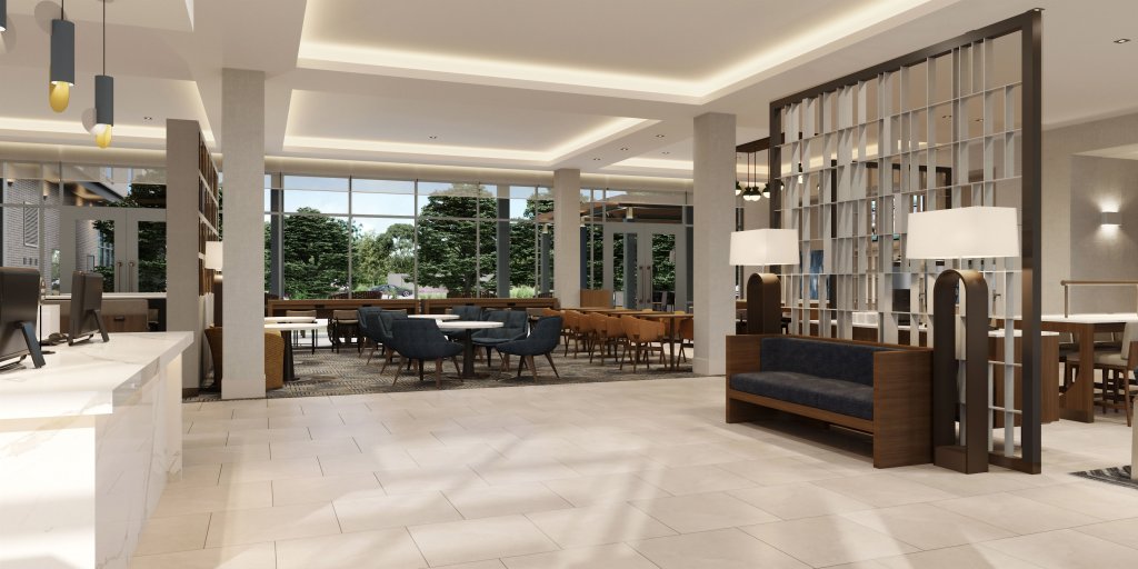 Modern hotel lobby with ample seating, marble reception desk, pendant lighting, and large windows with greenery views in a bright, elegant space.