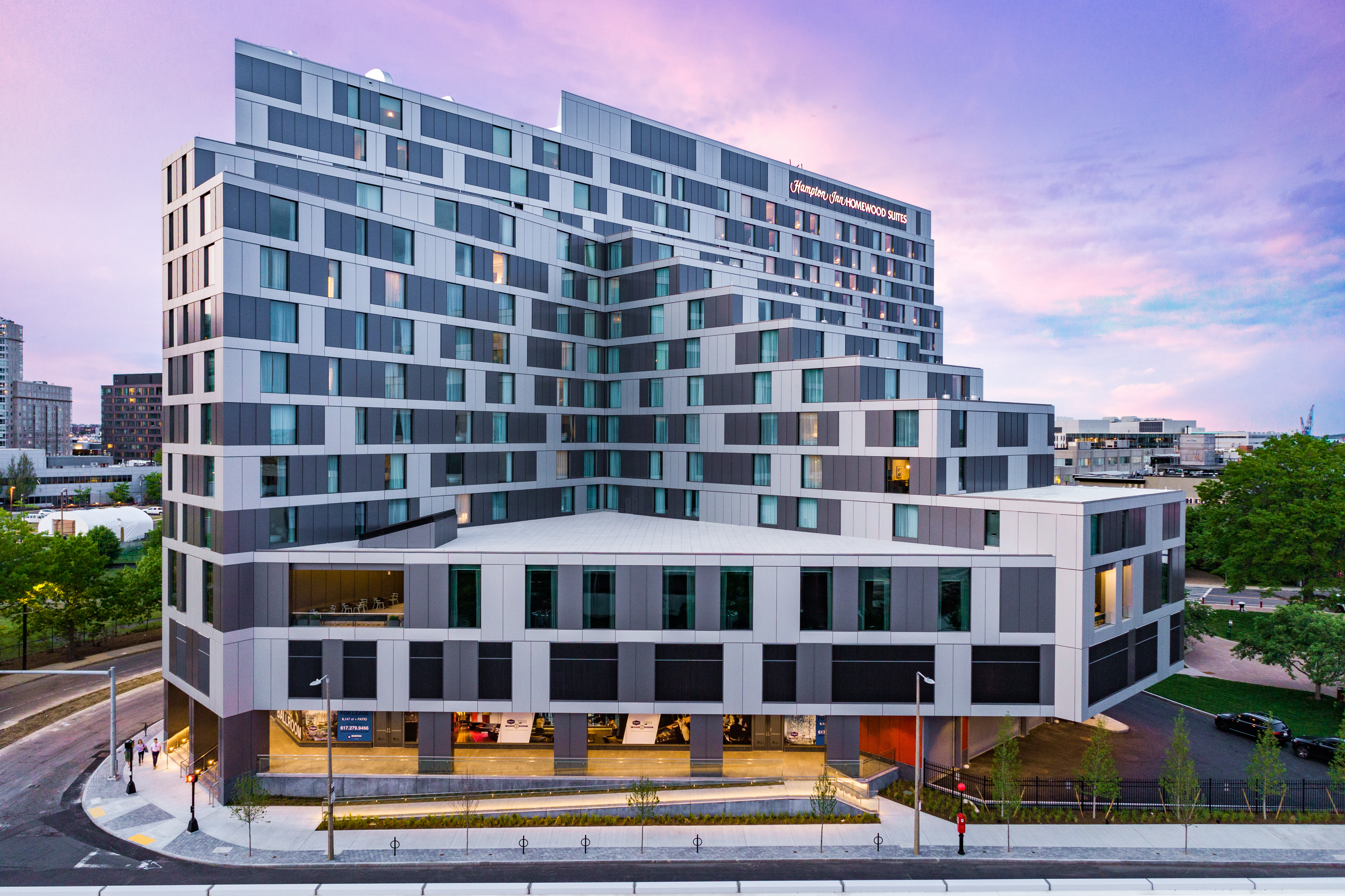 Modern multi-story Hampton Inn & Homewood Suites building at dusk with a purple and blue sky.
