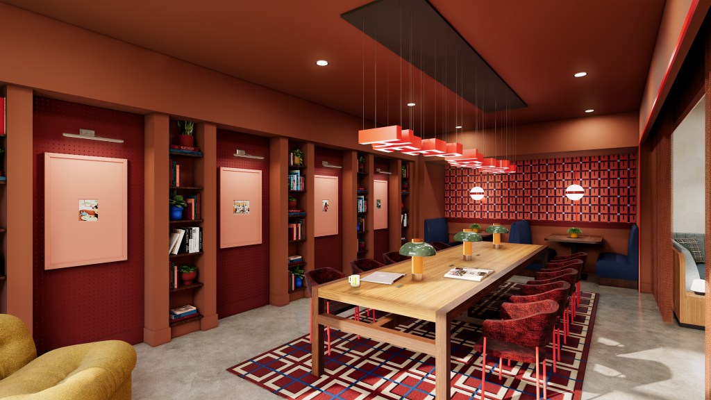 Modern conference room with a long wooden table, red upholstered chairs, patterned rug, and warm red-toned walls with built-in shelves.