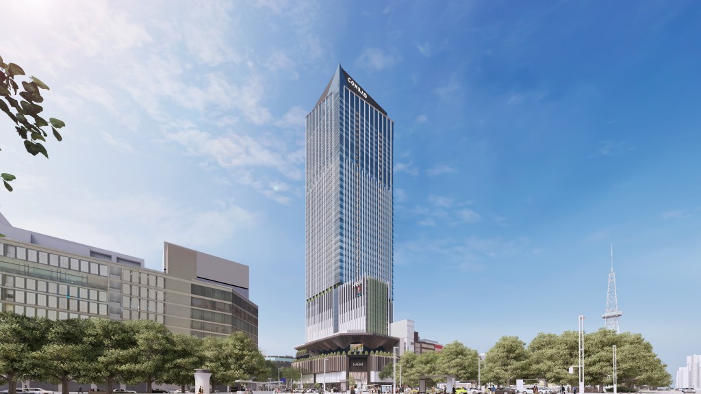 Tall modern skyscraper of the Conrad Nagoya with "Conrad" signage at the top, surrounded by trees and other buildings.