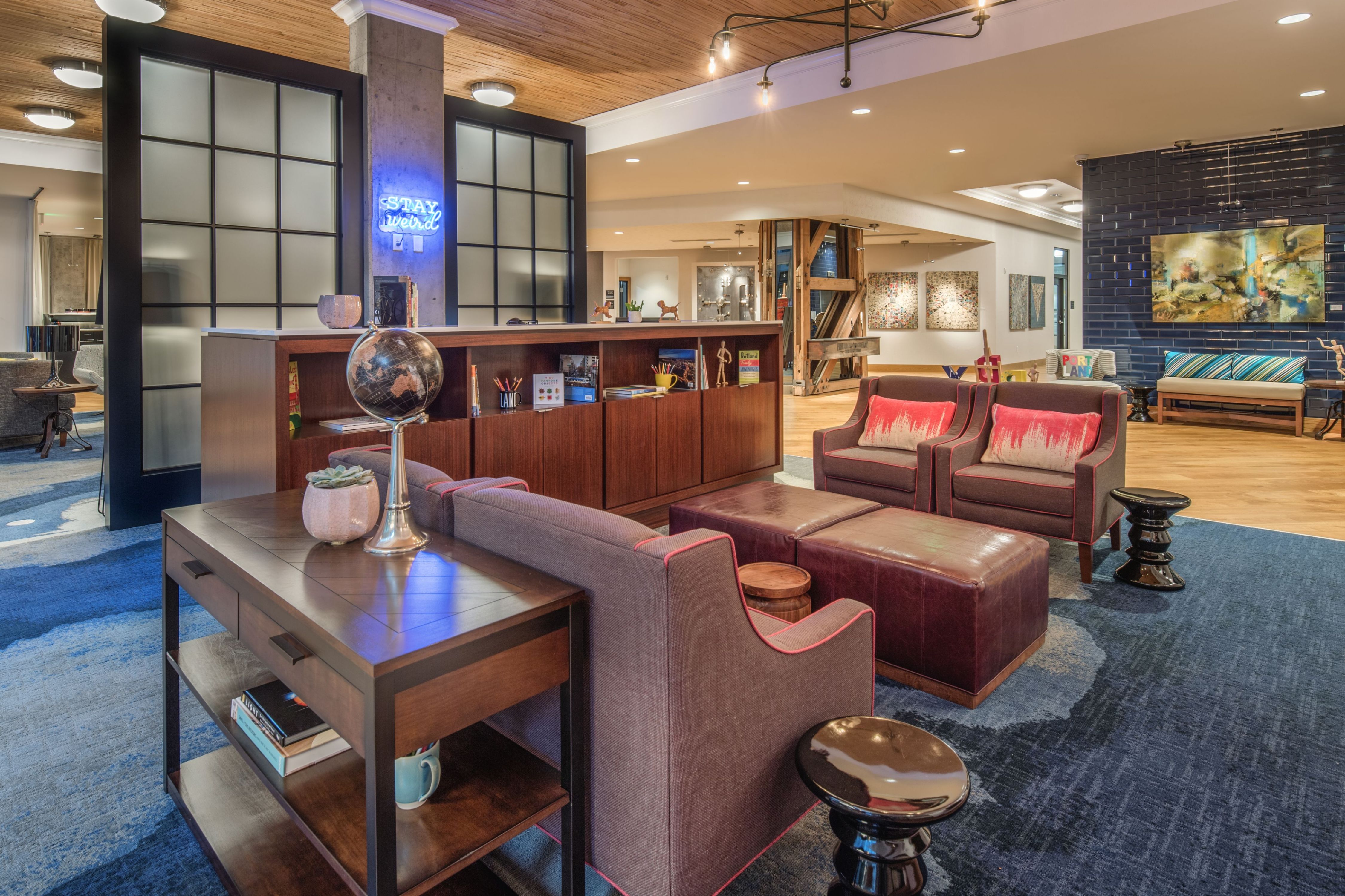 Modern lounge area with armchairs, a sofa, leather ottomans, a wooden globe stand, and a blue carpet.