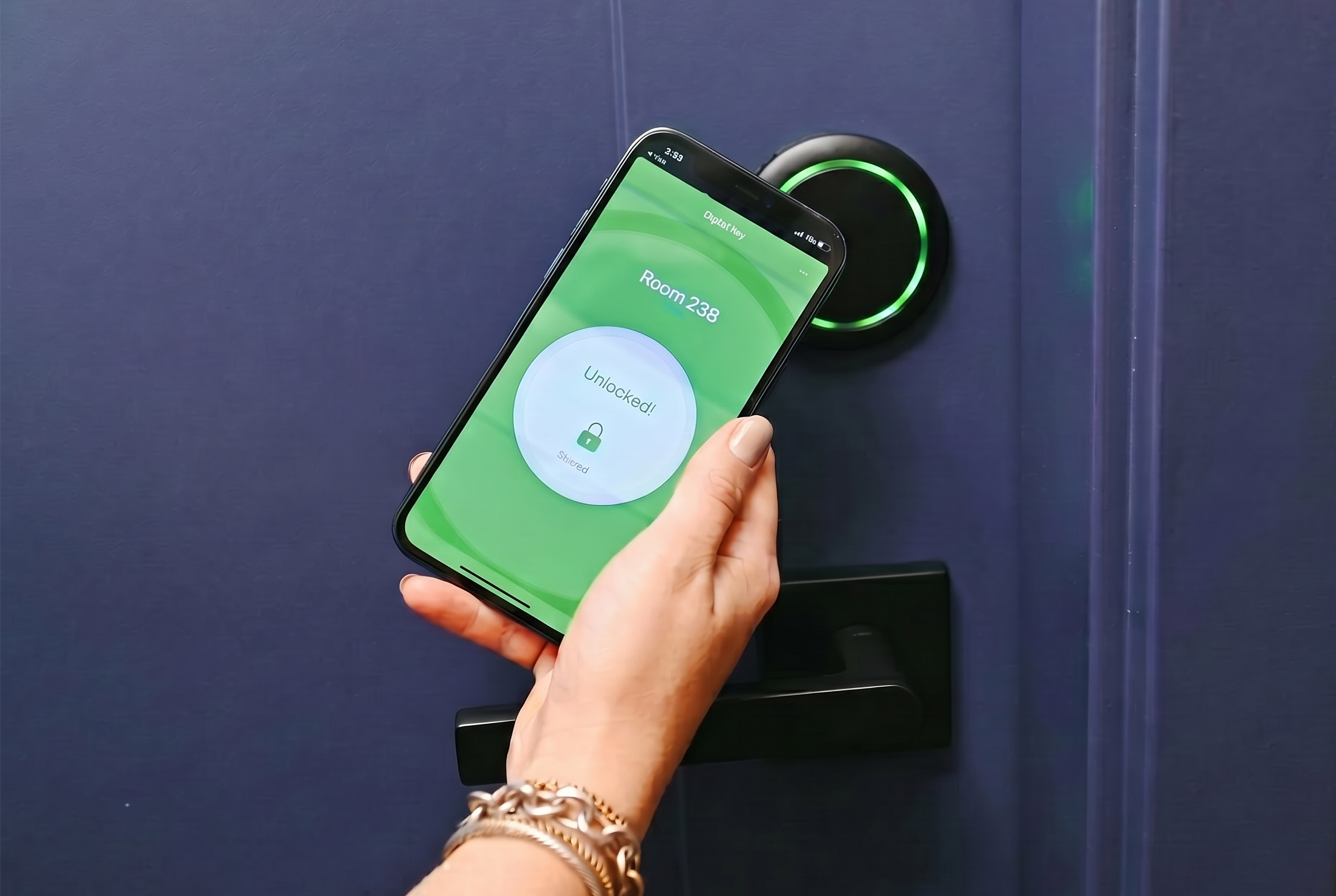 Hand holding a smartphone displaying a digital key app unlocking Room 238 on a dark blue door with a smart lock.