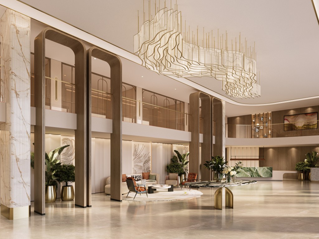 Spacious modern lobby at the Hilton Lucknow Gomti Nagar with marble columns, wooden arches, elegant chandelier, and seating area with chairs and sofa..