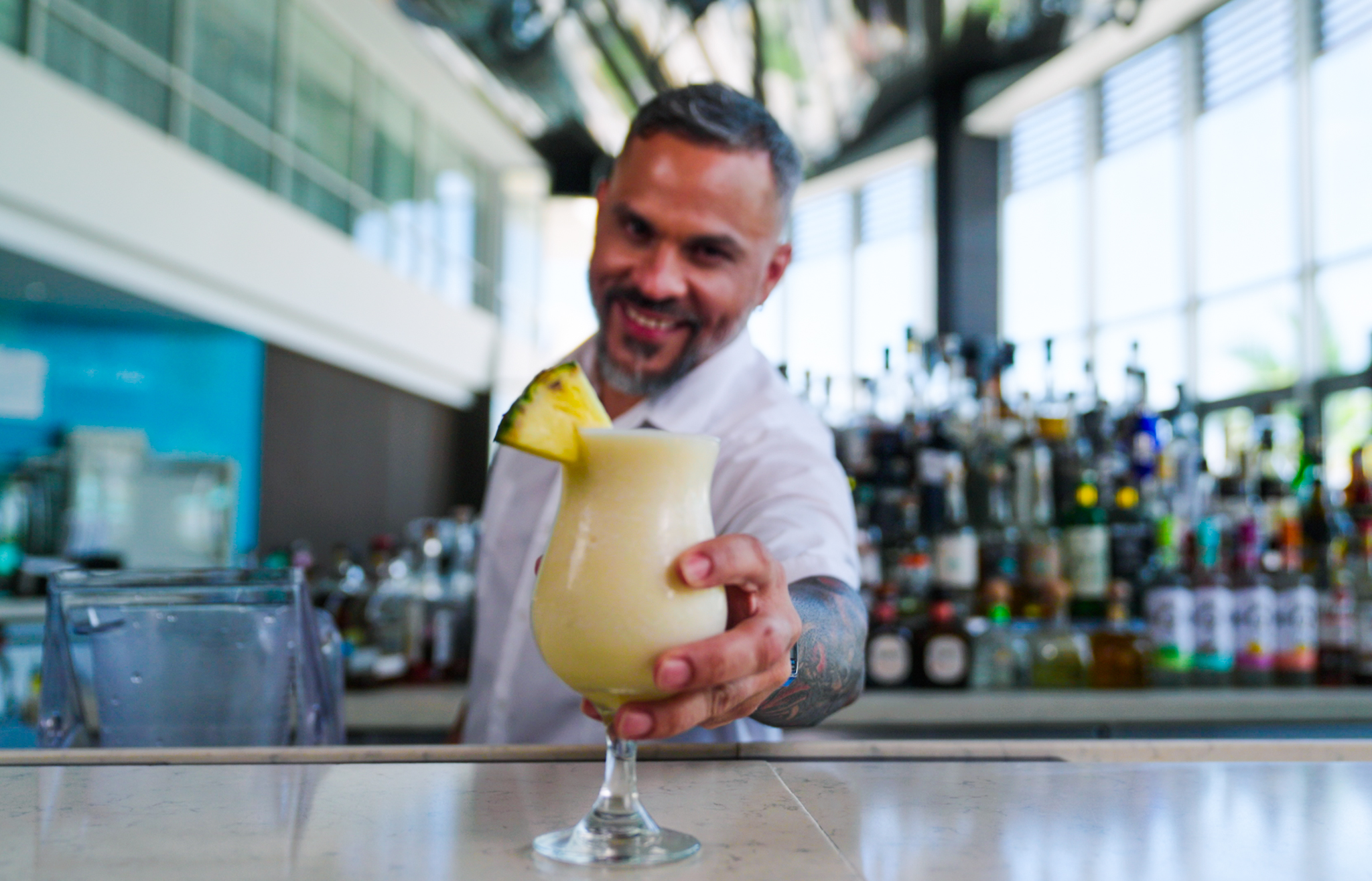 Bartender holding out a Piña Colada at Caribe Hilton