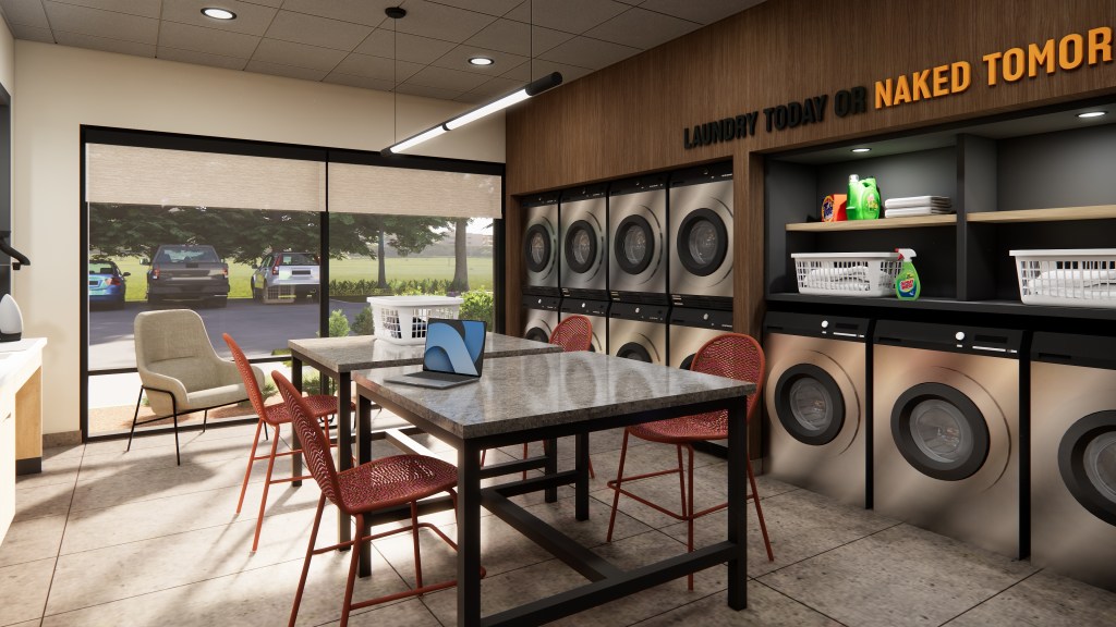 LivSmart Studios by Hilton - Laundry room with multiple washers and dryers, a table with red chairs, a laptop, laundry baskets, and cleaning supplies on shelves.