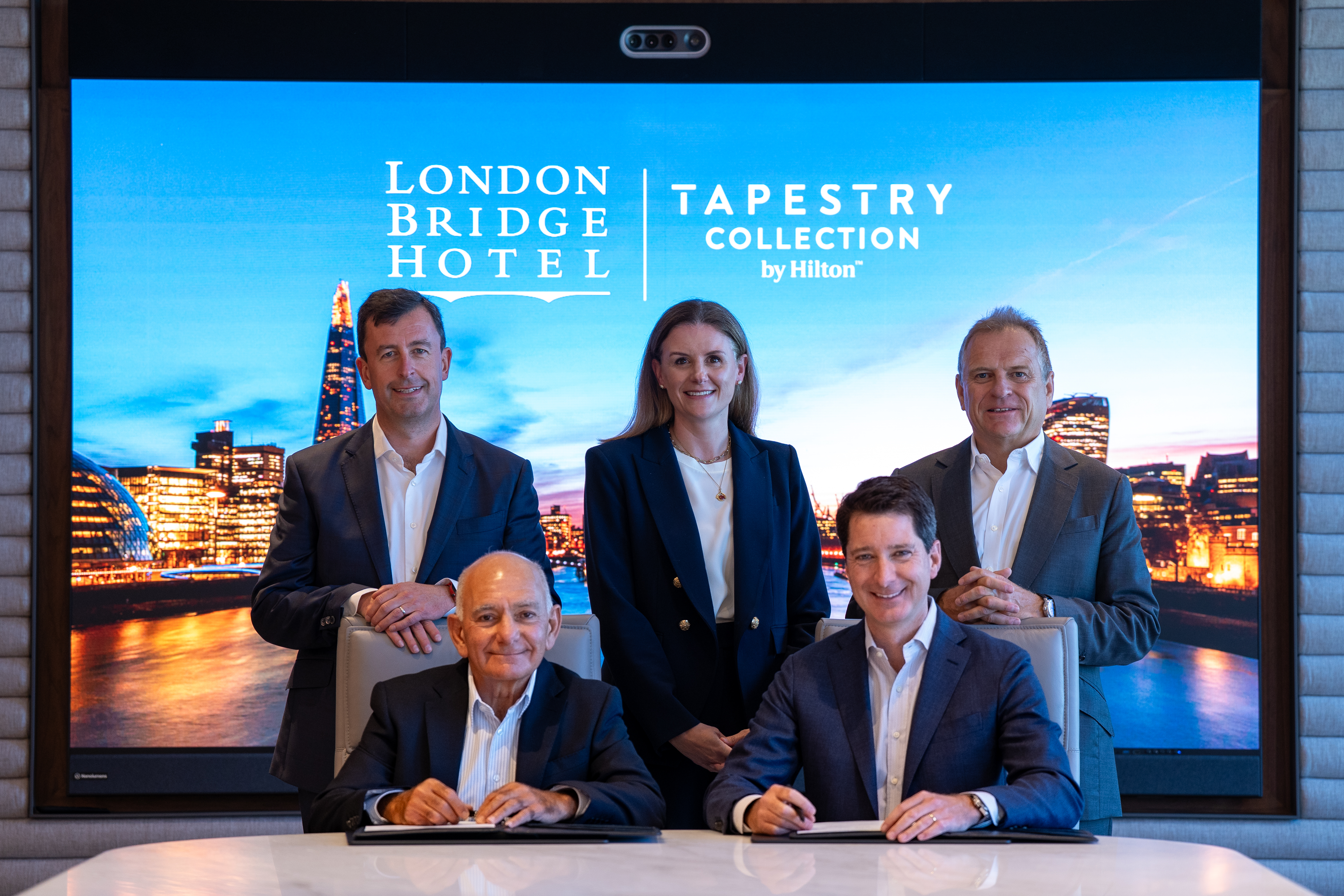 Five business executives pose at the London Bridge Hotel, Tapestry Collection by Hilton Signing Ceremony.