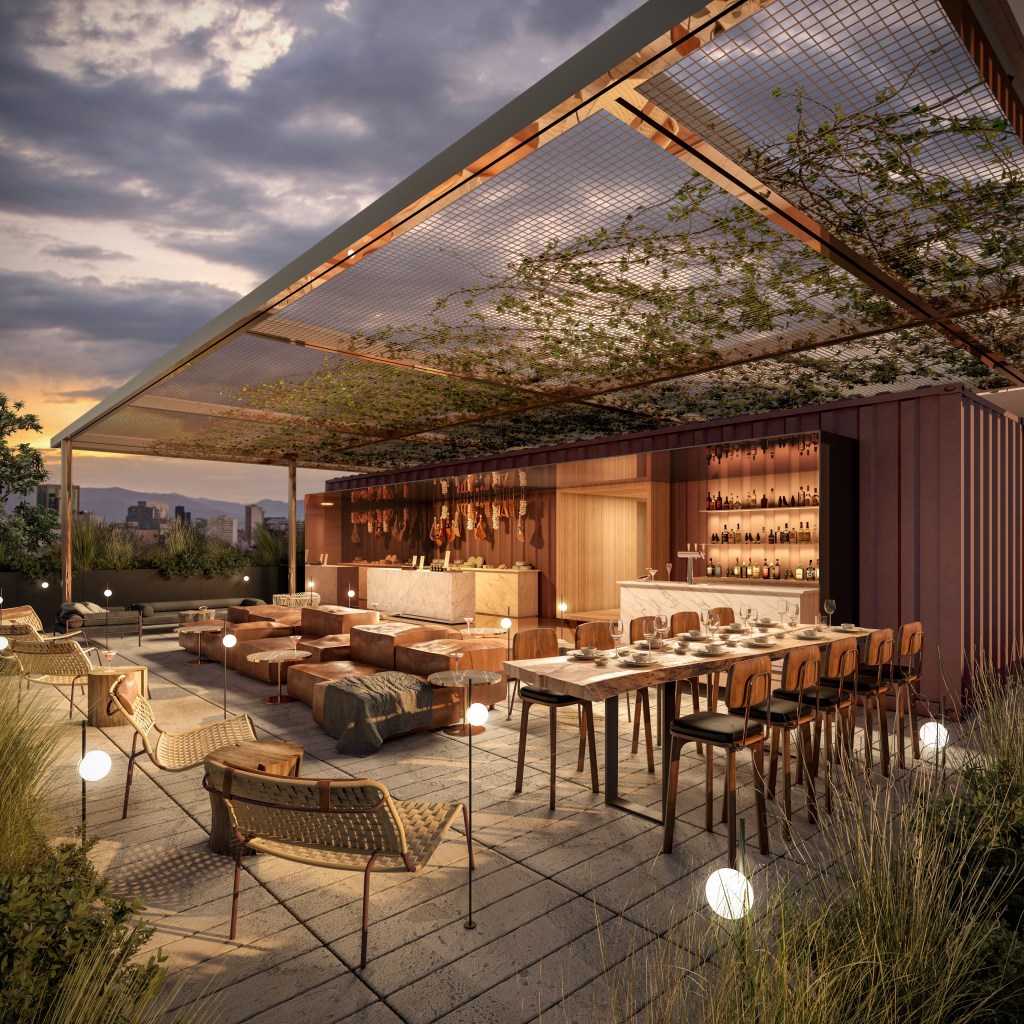 Modern outdoor rooftop lounge with wooden furniture, a bar, hanging plants on a metal canopy, and city skyline at sunset.