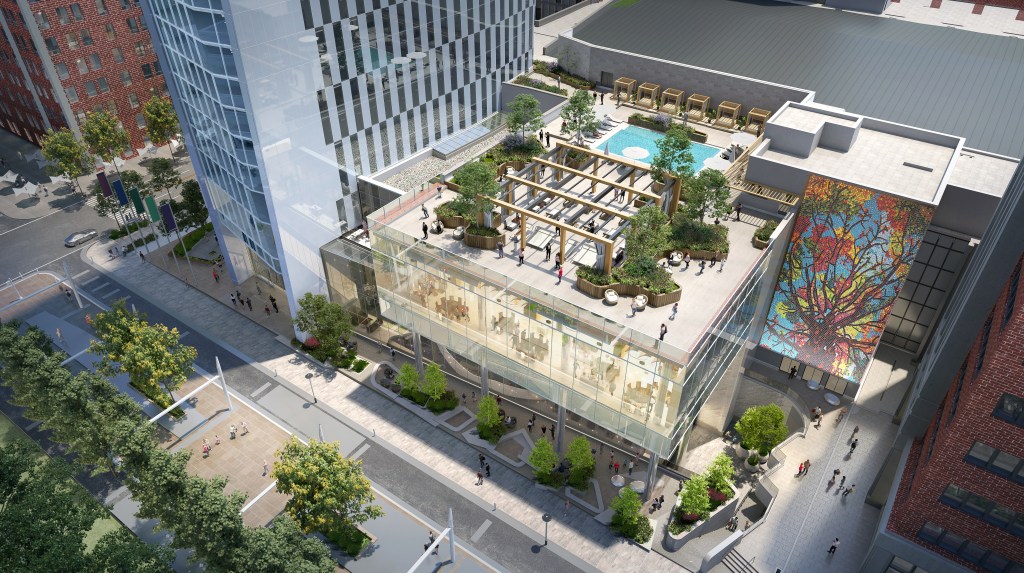 Rooftop terrace at the Signia Hilton Indianapolis with seating, greenery, and a pool atop a modern glass building in an urban area with people walking nearby.